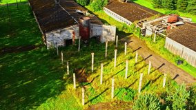 Old Abandoned Farm Buildings and Tall Concrete Posts on Overgrown Green Field - Powered by Shutterstock - Get 15% off with code: PIKWIZARD15