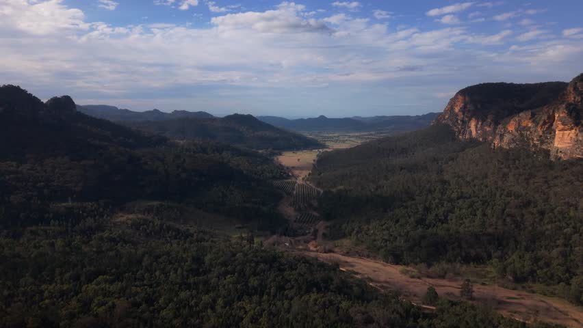 Cinematic flyover of ridge lines at sunset with long shadows cast over valleys and dense forests, Blue Mountains NSW Australia aerial establish
