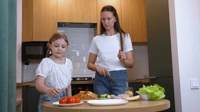Mom carefully slices cucumber while preparing sandwiches with her daughter, demonstrating cooking skills and enjoying quality family time in their modern kitchen - Powered by Shutterstock - Get 15% off with code: PIKWIZARD15