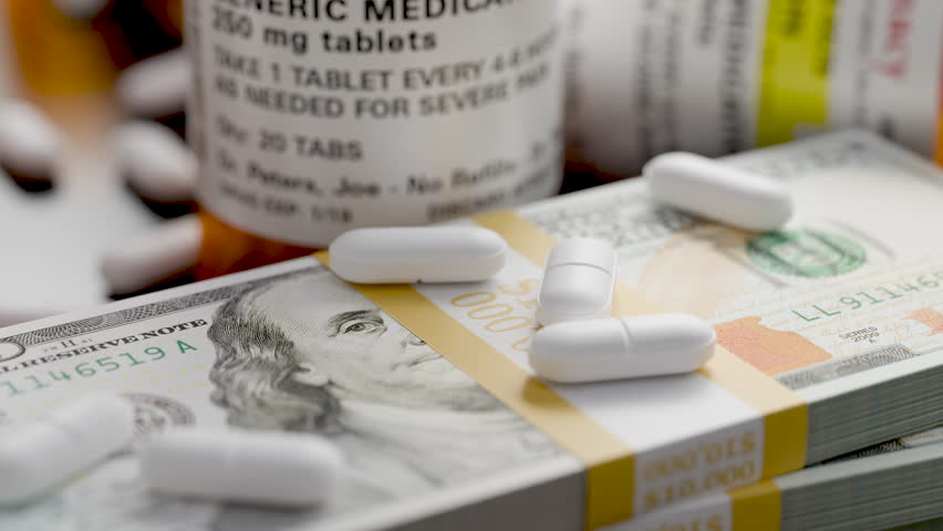 Prescription Medicine Bottles and Pills Next To Stacks of 100 Dollar Bills.