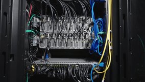 Inside a server rack in a data center: rows of active servers with glowing green LEDs, surrounded by a complex web of blue, yellow, and black network cables. A detailed, high-tech view of the core  - Powered by Shutterstock - Get 15% off with code: PIKWIZARD15