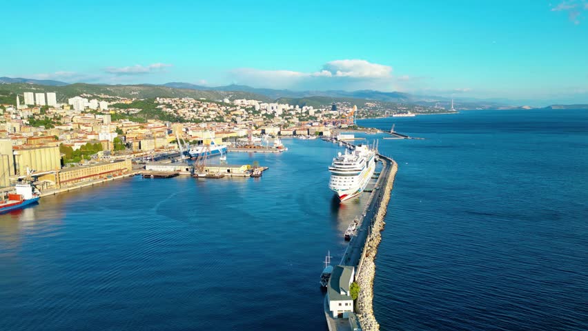 AIDAblu cruise ship docked in the port of Rijeka, Croatia, captured from a drone with the city and mountains in the background on a sunny day