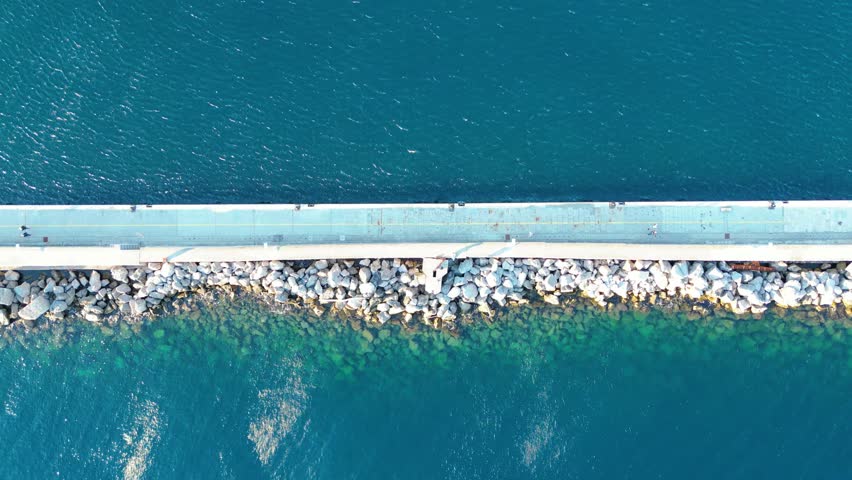 Aerial view of Molo Longo pier in Rijeka, Croatia. The breakwater with walking path, rocks, and clear Adriatic waters captured from above