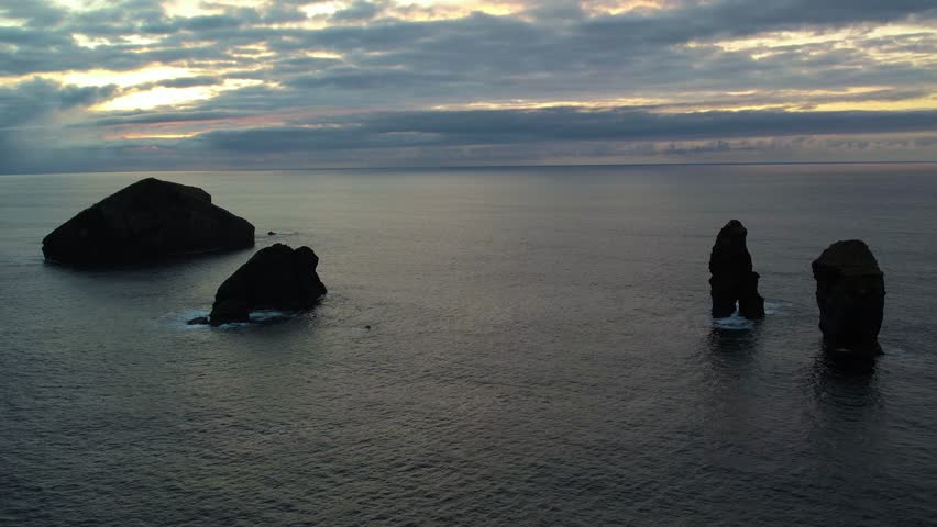  Volcanic sea stacks rise from ocean at sunset