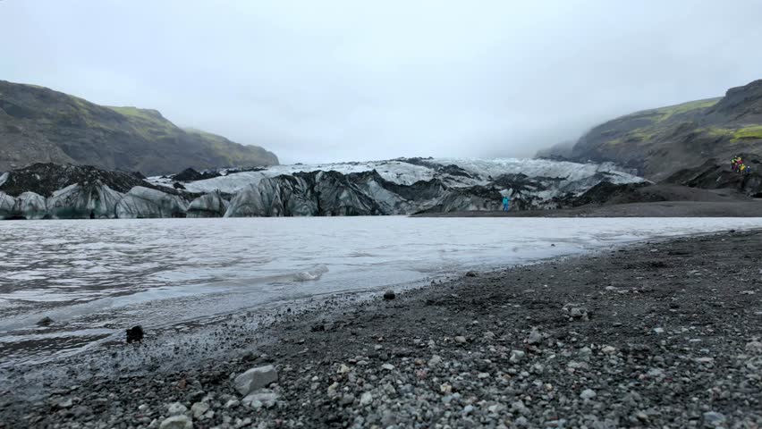 Glacial landscape captures the gradual melting of ice, with water flowing steadily across rocky terrain, the interaction between land and water in a serene natural environment filled with textures