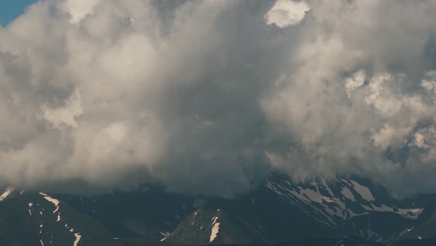 Beautiful mountain landscape. High-mountain massif, clouds over mountain peaks. Mountain slope inside a cloud, nature at a height