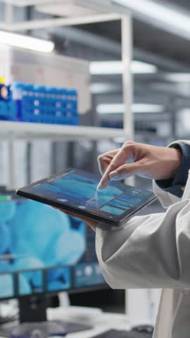 Vertical Video Close up of tablet running important experiment data in a research lab, man scientist studies experiment. Biotechnology, genetics research and pharmacology for progress in chemistry