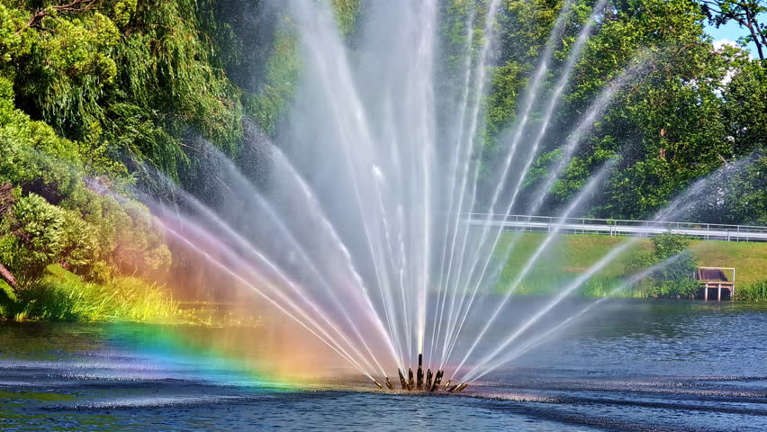 Vibrant Rainbow in Close-Up of Fountain Water Spray Against Green Background