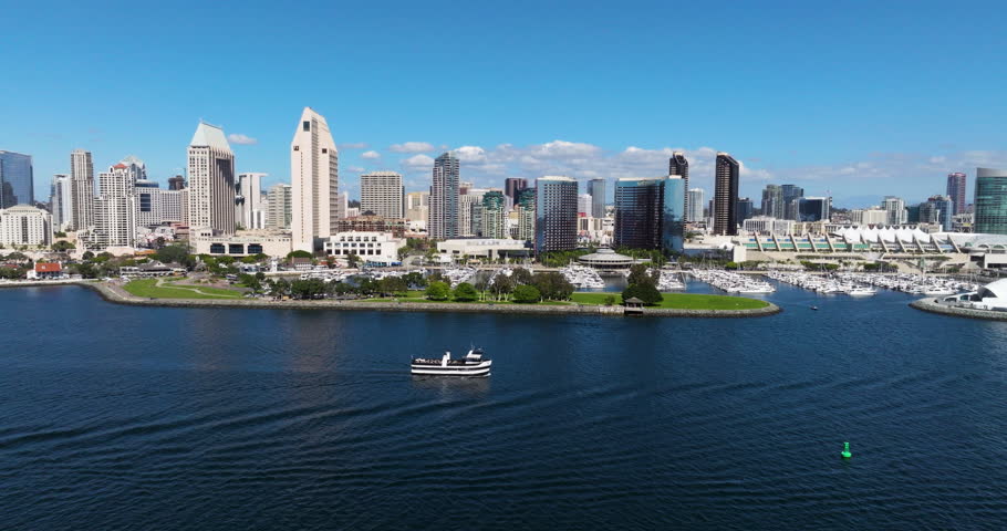 San Diego Skyline From The San Diego Bay With Boat Navigating In The Calm Water In California, USA. - aerial shot