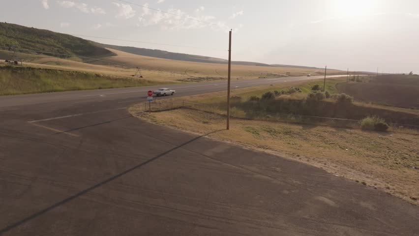 Drone shot of a vintage car driving into the sun in Montana