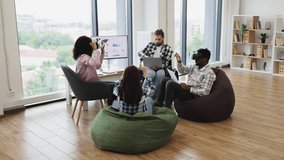 Diverse group of adults in modern office interacting with virtual reality glasses, analyzing data - Powered by Shutterstock - Get 15% off with code: PIKWIZARD15