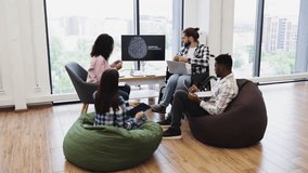 Group of men and women collaborating on artificial intelligence presentation in relaxed office. Includes professionals with diverse backgrounds, surrounded by beanbags, using digital technology - Powered by Shutterstock - Get 15% off with code: PIKWIZARD15