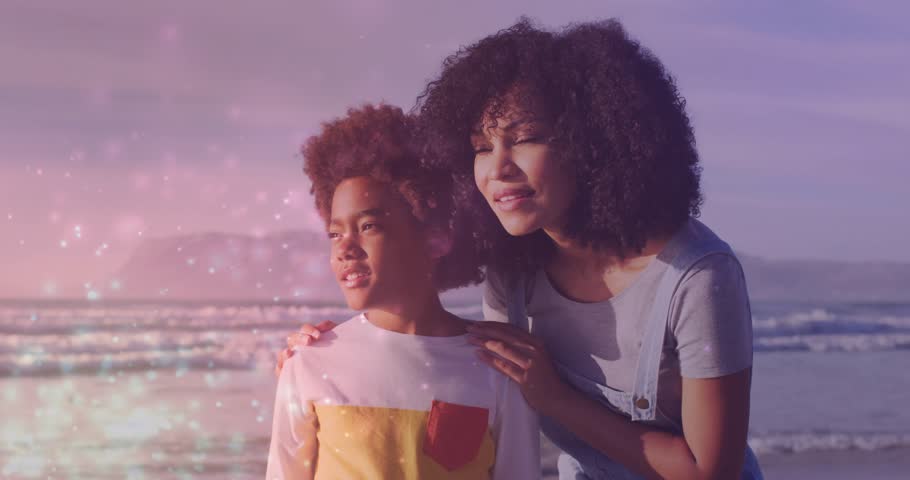 Mother placing hands on boy's shoulder on beach, guiding ocean spotting with sparkles in education. Coastal, mentorship, aspiration, emotional, scenic, supportive, adventure