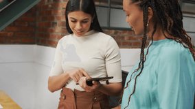 Two women collaborating on tech interface in office tapping device while reviewing icons emerging. Technology, innovation, teamwork, collaboration, digital, interface, communication - Powered by Shutterstock - Get 15% off with code: PIKWIZARD15