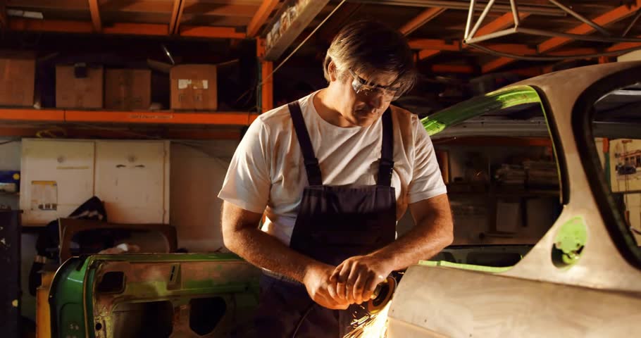 Automotive technician picking up grinder and smoothing rusted car panel with pulsing cosmic sparks. Mechanic, workshop, industrial, craftsmanship, durability, innovation, precision