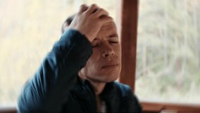 A man sits with visible discomfort, holding his head while enduring a painful migraine. Ideal 4K video for medical, health awareness, and emotional stress-related content. - Powered by Shutterstock - Get 15% off with code: PIKWIZARD15