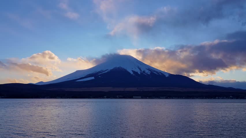 Timelapse of clouds drifting over Mount Fuji during golden hour.