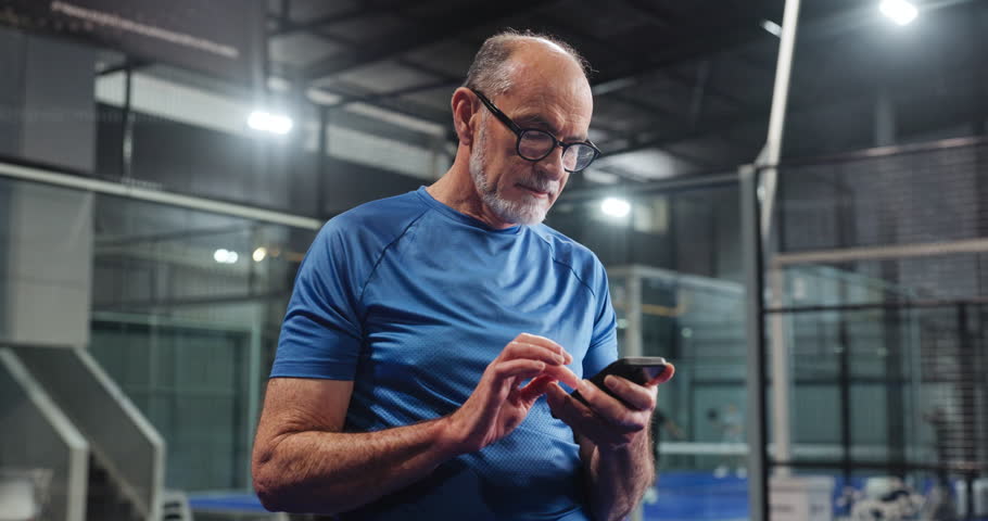 Typing, coach or elderly man in club with phone, scroll or message update during training break. Digital, sport or old person in court with mobile, tournament results or tennis tips on social media.