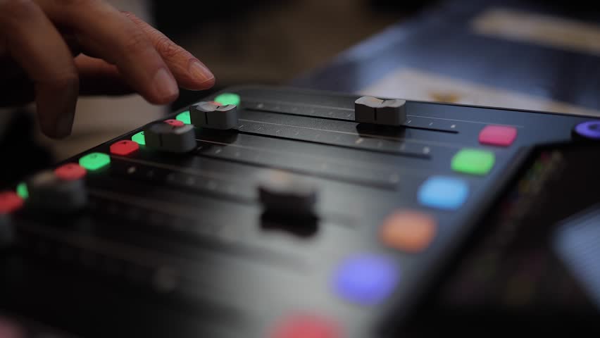 Audio mixer: Fingers slide tracks 2 and 3 faders on sound console