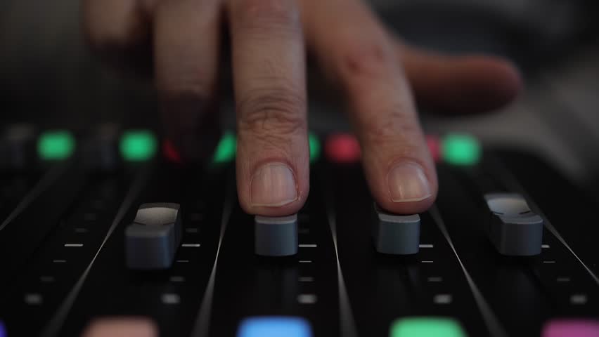 Selective focus audio mixing console, fingers slide track faders up