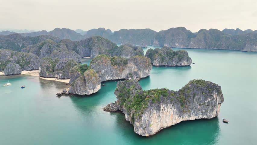 Turquoise waters surround towering limestone islands in Ha Long Bay, Vietnam, flying over the limestones