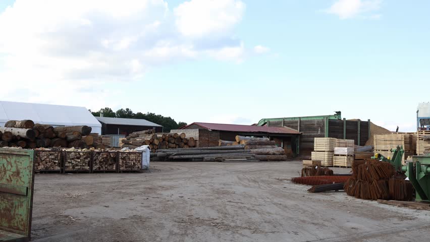 Industrial lumber yard with piles of cut logs wooden pallets and firewood storage under blue sky symbolizing forestry industry timber processing natural resources supply and woodworking business