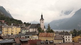 Church tower with clock rises above colorful houses of alpine village near mountain lake under cloudy misty sky creating serene European scenery with tradition history and timeless architectural charm - Powered by Shutterstock - Get 15% off with code: PIKWIZARD15