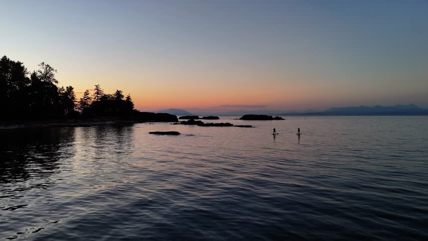 Smooth aerial drone flight skimming over the ocean surface near Neck Point, Nanaimo, showcasing gentle waves and rocky shoreline