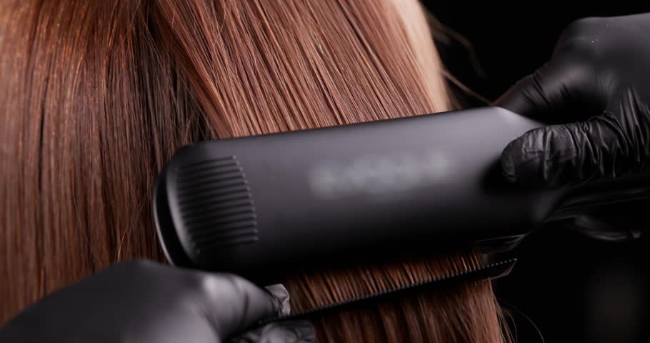 Sleek hair straightening process with stylist using professional flat iron.