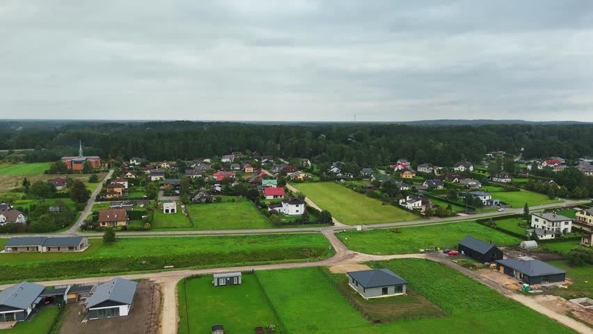Ikskile revealing low-density housing forest edge and Daugava River corridor blending suburban expansion with natural terrain in Vidzeme region, central Latvia, drone pan.