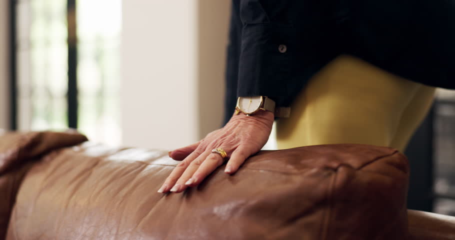 Woman, touch and leather sofa in holiday home for comfort, texture and reflection on good memories. Hand, couch and female person in vacation rental with satisfaction, pride and care for property.