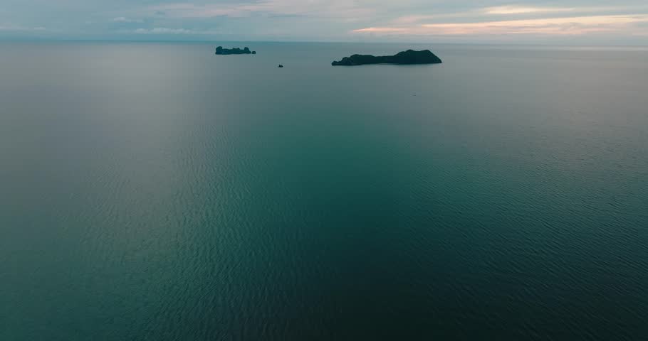 Aerial tilt-up over sea reveals islands near Ko Tao, Thailand, under soft skies.