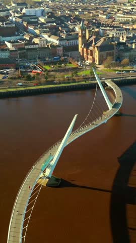 Wide overhead social ratio aerial of the Peace Bridge over the River Foyle in Derry, AKA Londonderry in Northern Ireland. Filmed in 1080x1920, 60FPS and with Rec709 color.