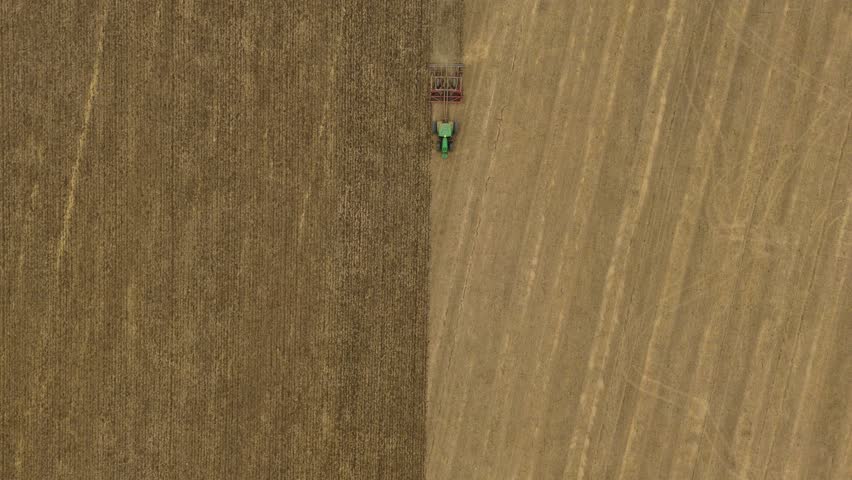 Aerial drone footage top down of tractor ploughing farm field in Bedfordshire UK, agriculture, crop planting, soil preparation and rural countryside