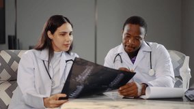Two diverse doctors collaborate in a medical hospital, examining test results and discussing X-ray scans and use tablet computer. They focus on patient health and treatment strategies. - Powered by Shutterstock - Get 15% off with code: PIKWIZARD15