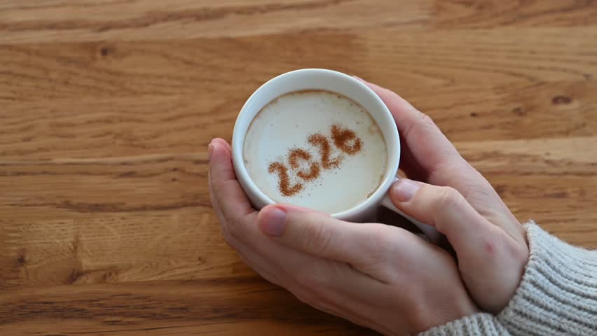 Woman in warm sweater enjoying coffee with 2026 on foam