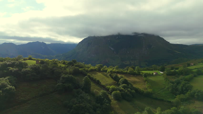 Green hills farmland and mountain with low clouds