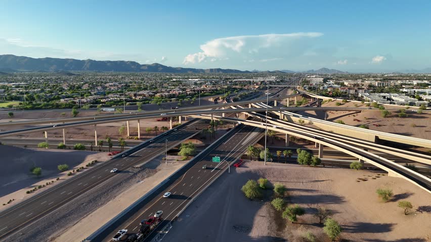 Aerial View of Highway interchange in Chandler Arizona, Interstate 10, Arizona State Route 202, South Mountain, early evening, blue sky with couple clouds, cars driving on road