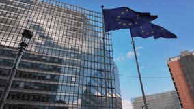 EU flags flutter outside modern office buildings with the Berlaymont headquarters in Brussels. - Powered by Shutterstock - Get 15% off with code: PIKWIZARD15