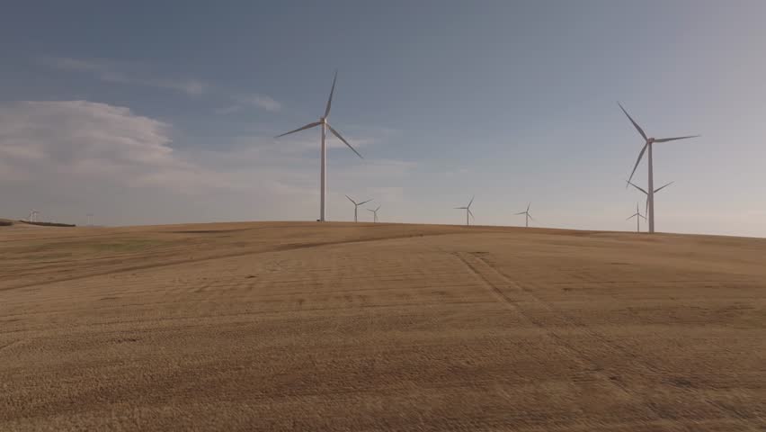 Drone shot of a golden field filled with windmills at sunset in Montana