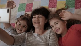 Video Call Family Selfie. Portrait Mother and Kids Kissing on Camera. Happy Mother With Her Kids are Making Selfie or Video Call to Father or Relatives in Bed. Technology, New Generation Parenthood. - Powered by Shutterstock - Get 15% off with code: PIKWIZARD15