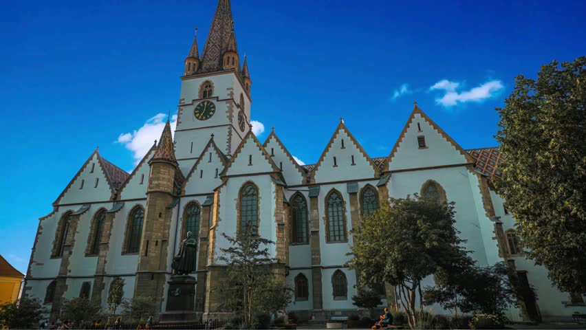 Sibiu , Romania The Medieval Saxon City of Sibiu in RomaniaSibiu, Romania - 5 Aug, 2025: Stunning daytime view of the Lutheran Cathedral in Sibiu, Romania, against a clear blue sky. A monument stands 