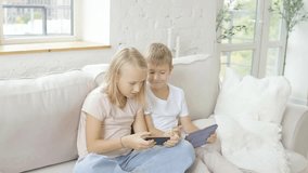 Two kids holding phone and tablet while playing mobile game browsing social media at home - Powered by Shutterstock - Get 15% off with code: PIKWIZARD15