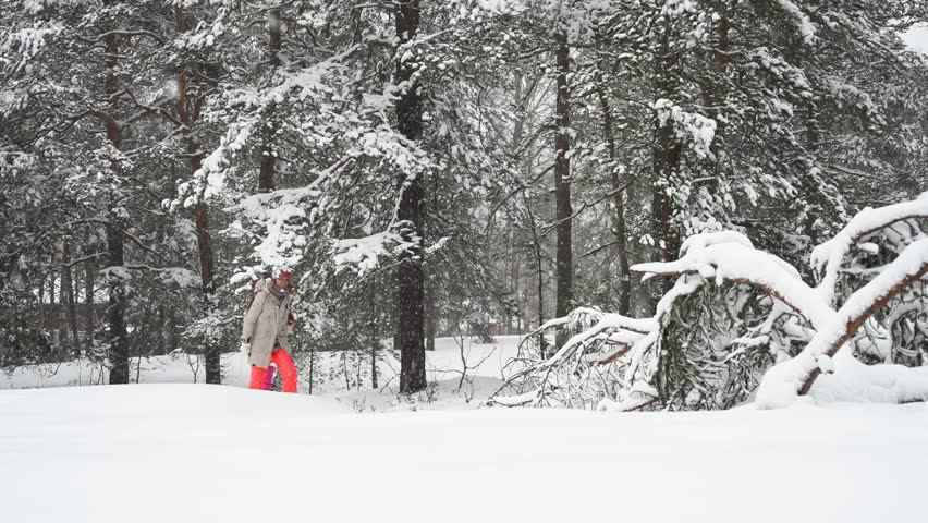 Middle-aged mother and teenage daughter enjoying walk in snowy Finland forest. Warm clothing, family values, lifestyle, togetherness and joyful winter holiday season atmosphere.