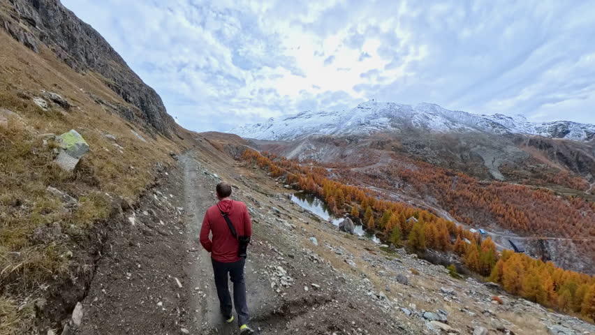 Following Man Uphill on Trail in Swiss Alps in Autumn
