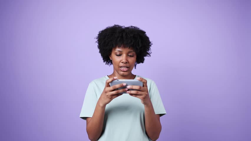 Young woman playing mobile game in slow motion on purple background