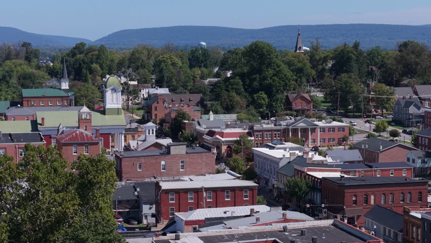 Experience the beauty of Charles Town, West Virginia as the drone flies over Main Street, showcasing the courthouse and vibrant neighborhoods on a sunny day.