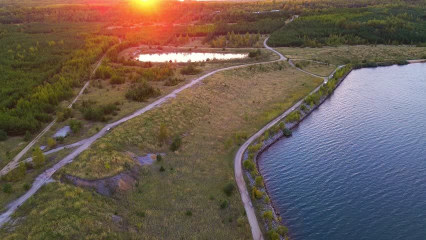 A bright aerial view of a bay on Lake Medard captures the shallow, colorful water contrasting with the surrounding paths and land during the late afternoon.