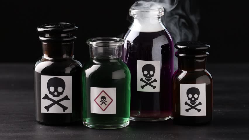 Bottles of poison with warning signs and smoke on dark table against black background