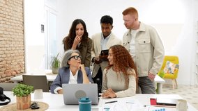 Multiethnic group of colleagues gathering around a laptop at a desk, discussing a project and analyzing data charts with their senior manager in a creative and collaborative modern workspace - Powered by Shutterstock - Get 15% off with code: PIKWIZARD15